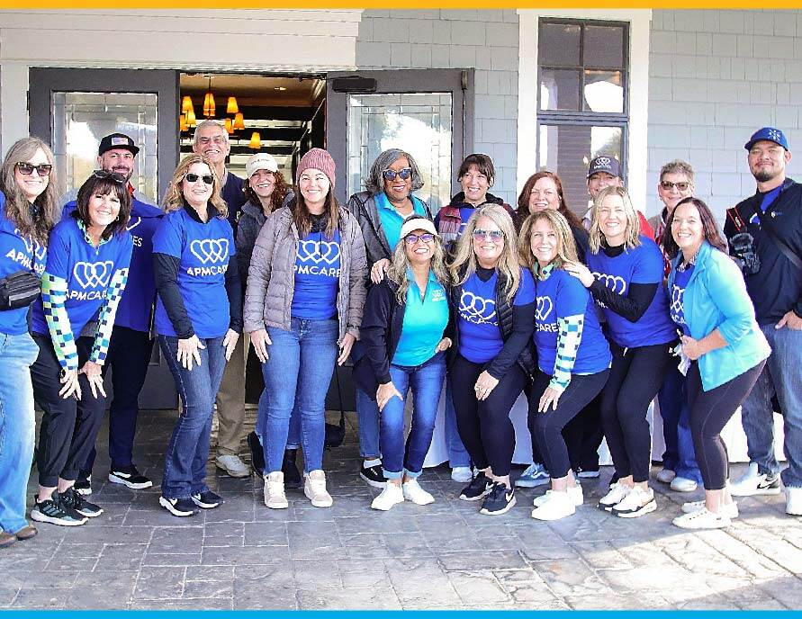 APM Cares volunteers standing together in a group at a community function